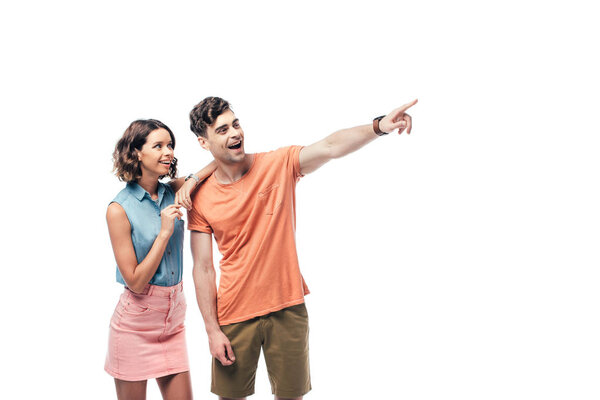cheerful man looking away and pointing with finger near smiling woman isolated on white