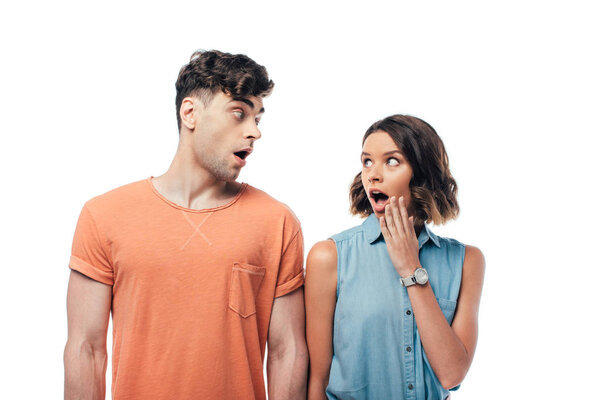 young, shocked man and woman looking at each other isolated on white