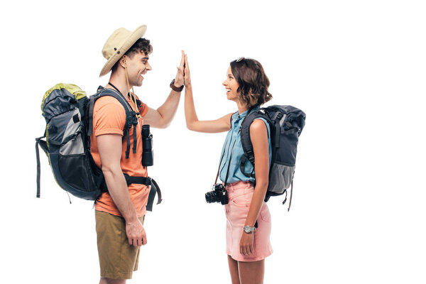 two cheerful tourists with backpacks giving high five isolated on white