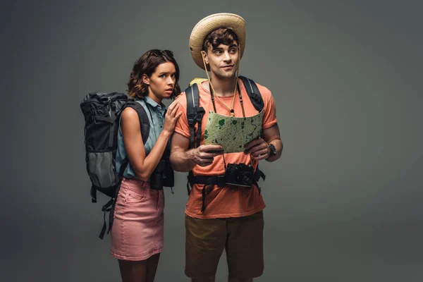 Smiling Touist Holding Geographic Map While Standing Scared Young Woman — Stock Photo, Image