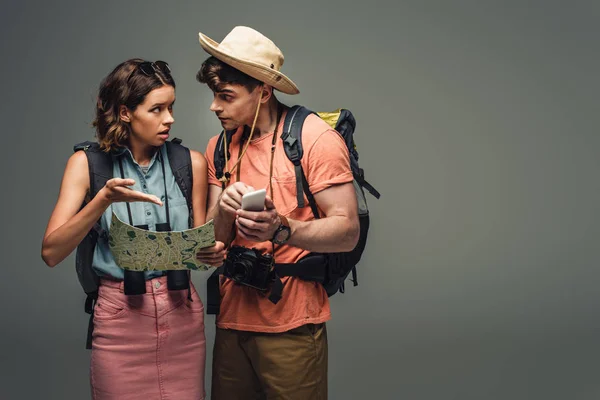 Двоє Молодих Туристів Розмовляють Зберігаючи Географічну Карту Сірому Фоні — стокове фото