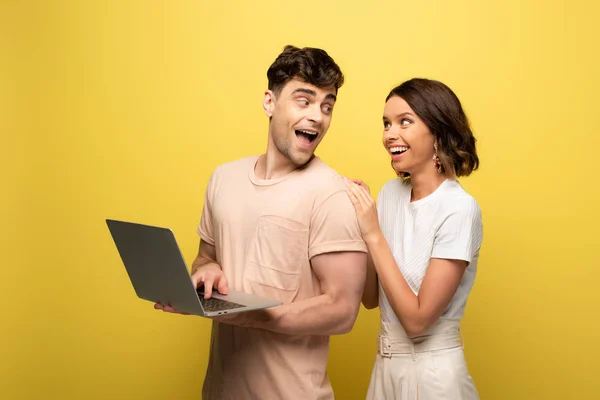 Щасливий Молодий Чоловік Використовує Ноутбук Стоячи Поруч Веселою Дівчиною Жовтому — стокове фото