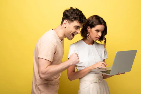 Happy Young Man Standing Attentive Girl Using Laptop Yellow Background — Stock Photo, Image