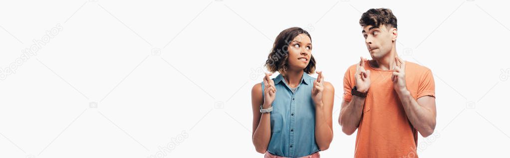 panoramic shot of young and woman holding crossed fingers and looking at each other  isolated on white