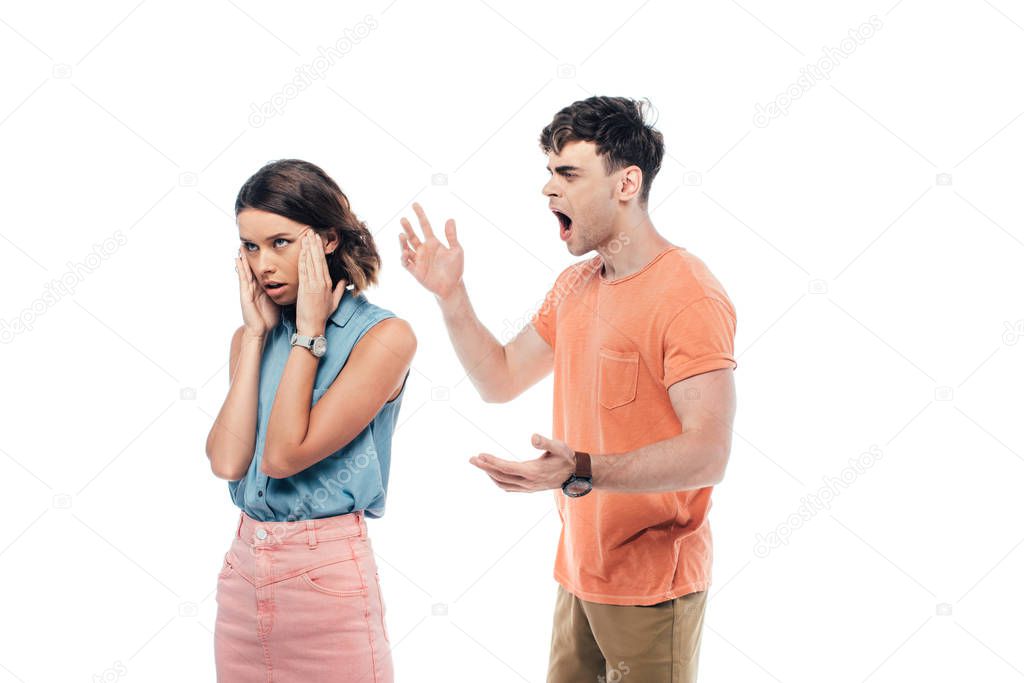 irritated young man gesturing while quarreling at offended girlfriend isolated on white
