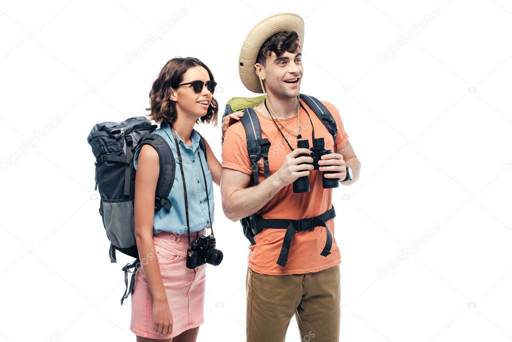 two young tourists with binoculars and digital camera looking away and smiling isolated on white