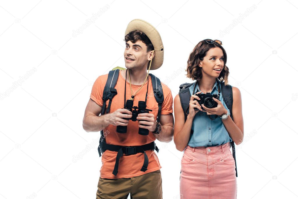 two cheerful young tourists with binoculars and digital camera looking away isolated on white