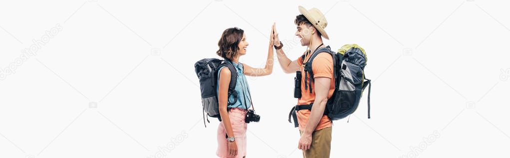 panoramic shot of two young tourists with backpacks giving high five isolated on grey