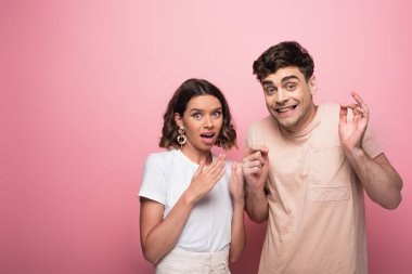 emotional man and woman gesturing shut up while looking at camera on pink background clipart