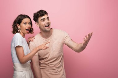 genç, heyecanlı erkek ve kadın gülümseyen ve pembe arka plan üzerinde uzağa bakıyor