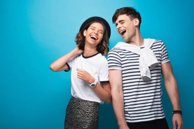 mutlu, trendy erkek ve kadın mavi arka plan üzerinde birlikte gülüyor