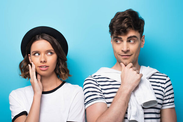 positive, young man and woman smiling at each other on blue background