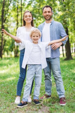mutlu aile kamera bakıyor ve parkta poz
