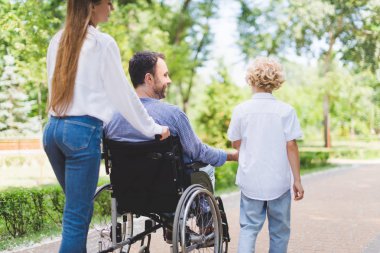 parkta engelli babası ile tekerlekli sandalye haddeleme anne geri görünümü 