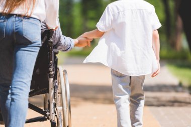 parkta tekerlekli sandalyede engelli babası olan anne ve oğlunun kısmi görünümü