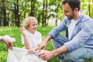 baba, anne ve oğlu parkta plastik torba içinde çöp toplama