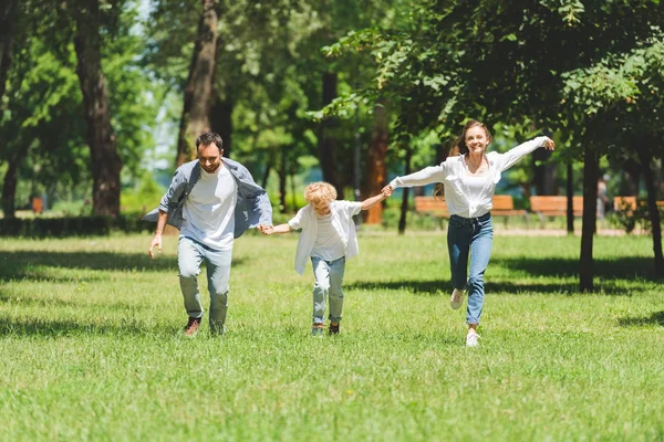 日中は手をつないで公園で走る興奮した家族 — ストック写真
