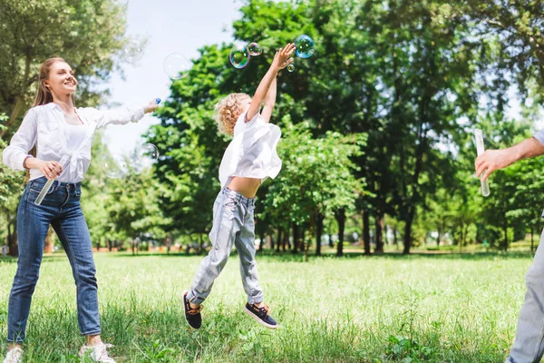 公園で石鹸の泡で遊ぶ母 父と息子 — ストック写真