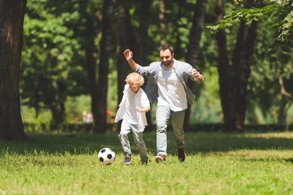 ハンサムな父と愛らしい息子は公園でサッカーをしています — ストック写真