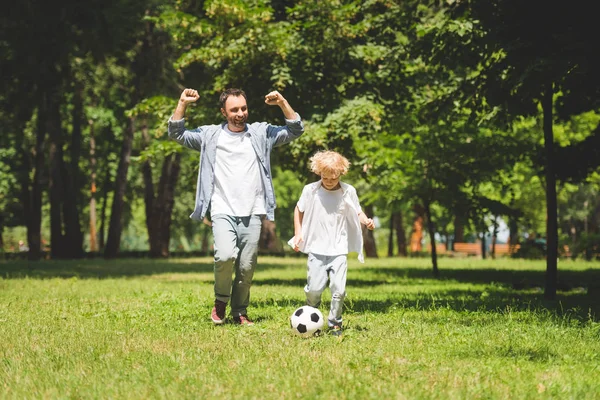 興奮した父と愛らしい息子は公園でサッカーをしています — ストック写真