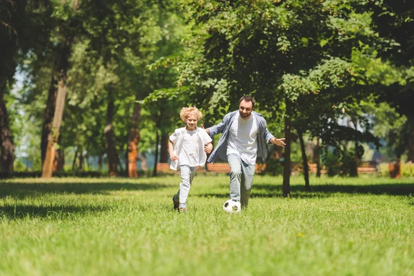 公園でサッカーボールでサッカーをしている父と愛らしい息子 — ストック写真