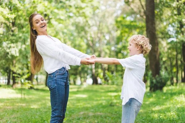 公園で手をつないで美しい笑顔のお母さんと息子 — ストック写真