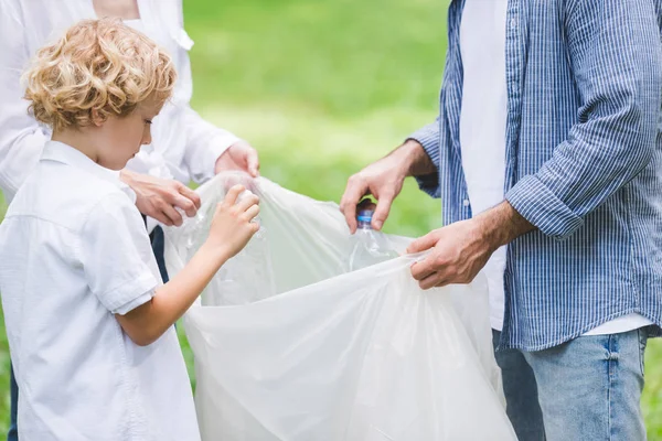 公園でビニール袋の中のゴミを拾う家族のトリミングビュー — ストック写真