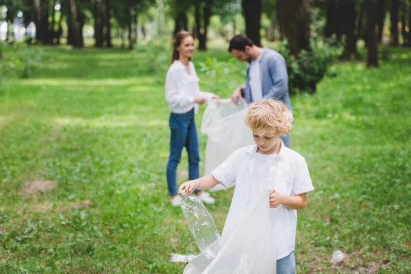 コピースペース付きの公園でビニール袋のゴミを拾う家族 — ストック写真