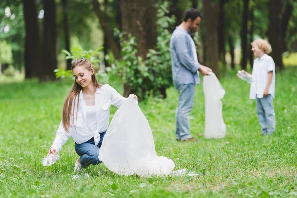 Uśmiechnięta Matka Ojciec Syn Zbierając Plastikowe Butelki Workach Parku — Zdjęcie stockowe