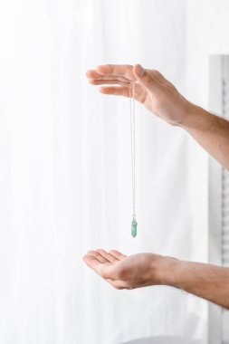 cropped view of hypnotist holding green stone in clinic clipart