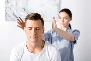 man sitting with closed eyes while healer cleaning his aura clipart