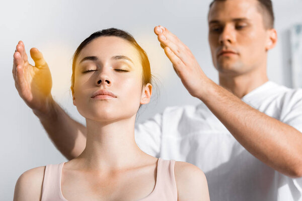 женщина сидит с закрытыми глазами, пока целитель чистит ее ауру
