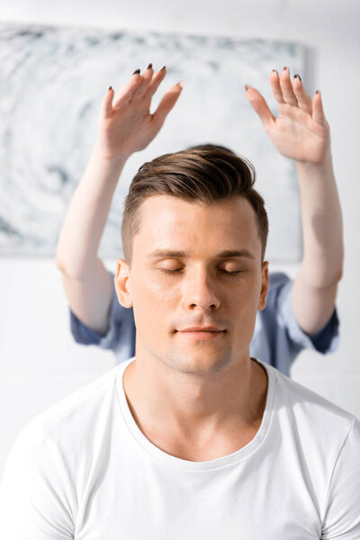 вид человека, сидящего с закрытыми глазами, пока целитель чистит свою ауру
