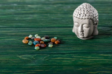 buddha statuette and colorful semiprecious stones on wooden surface clipart
