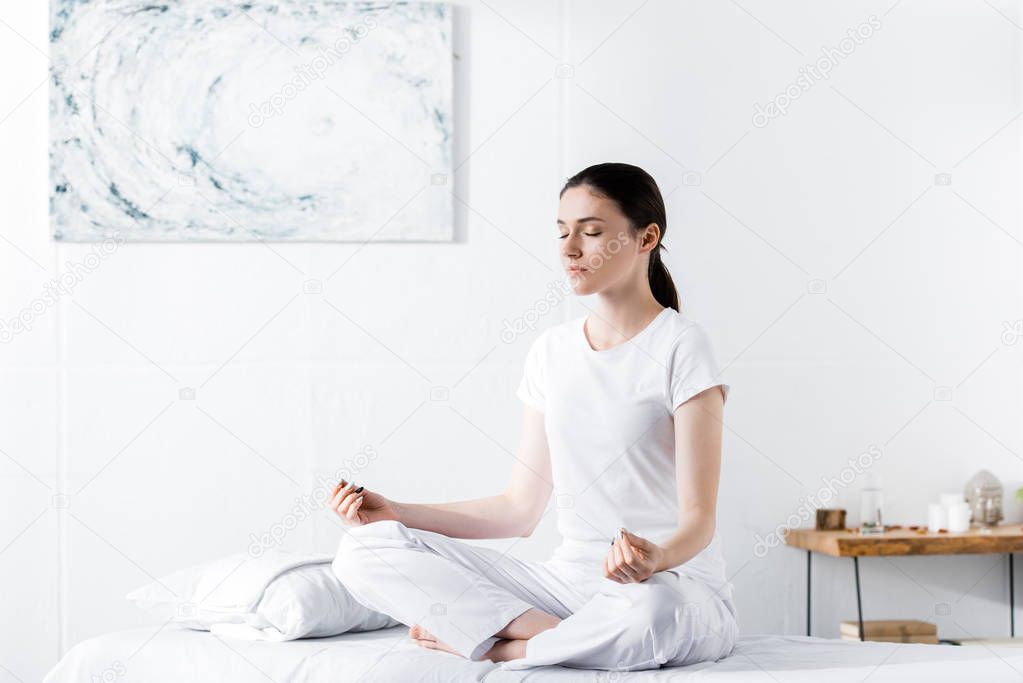 woman sitting on massage table in lotus pose with closed eyes