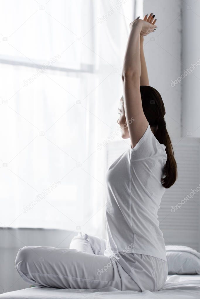 woman with ponytail sitting on bed and stretching in clinic