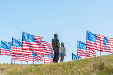 amerikan bayrakları yakınında kızı ile ayakta askeri üniformalı adam 