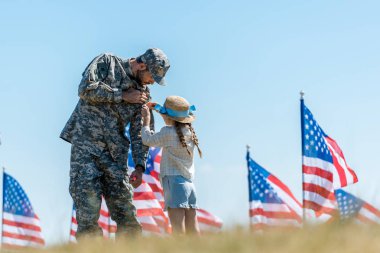 Amerikan bayrakları yakınında askeri baba üniforması dokunmadan çocuk seçici odak 