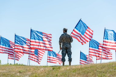 askeri üniforma ve şapka ayakta ve Amerikan bayrağı tutan askerin seçici odak 