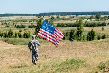 üniformalı asker çim üzerinde yürüyüş ve Amerikan bayrağı tutan 