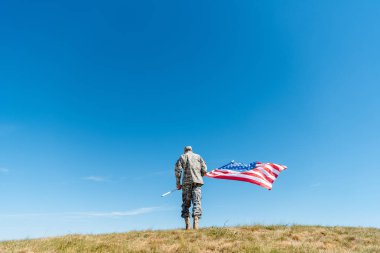 yıldız ve çizgili Amerikan bayrağı ile ayakta üniformalı askeri adamın arka görünümü 