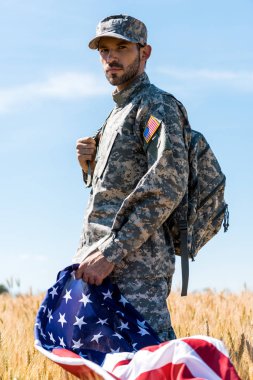 sahada dururken Amerikan bayrağı tutan üniformalı askerin seçici odak noktası 