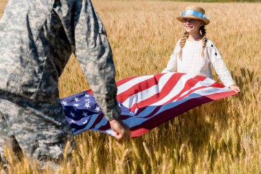 askeri üniformalı adam alanında sevimli kızı ile Amerikan bayrağı tutan kırpılmış görünümü 