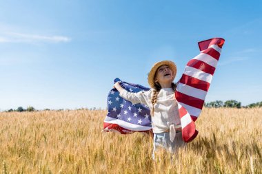 buğday ile altın alanda Amerikan bayrağı tutan hasır şapka neşeli çocuk 