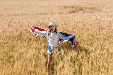 cute and happy kid holding american flag in golden field  clipart