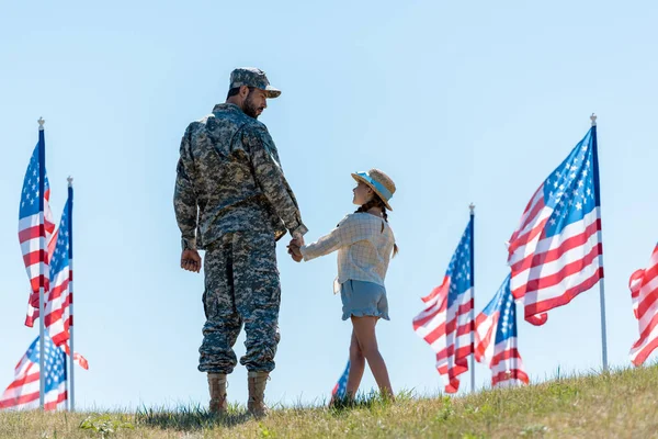 アメリカの旗の近くで娘と手をつないで軍服を着た父親 — ストック写真