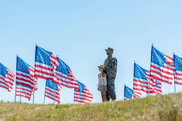 アメリカの旗の近くにかわいい子供と立って軍の制服で父親の選択的な焦点 — ストック写真