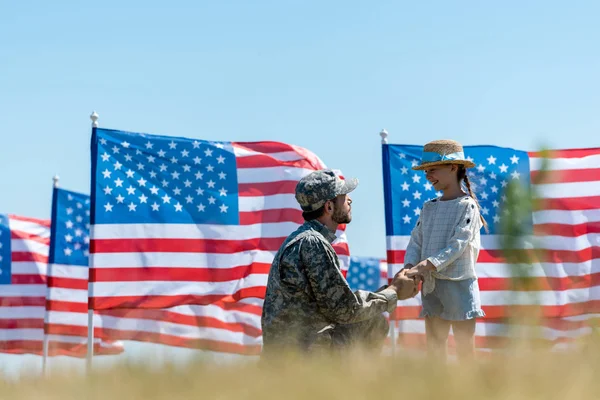 アメリカの旗の近くで陽気な子供と手をつないでいる軍の父親の選択的な焦点 — ストック写真