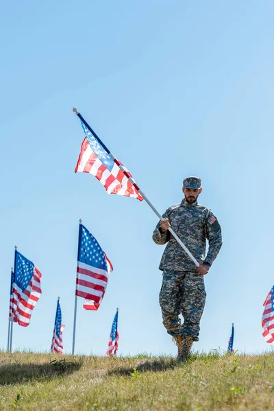 軍服と帽子をかぶったハンサムな兵士がアメリカ国旗を掲げる — ストック写真