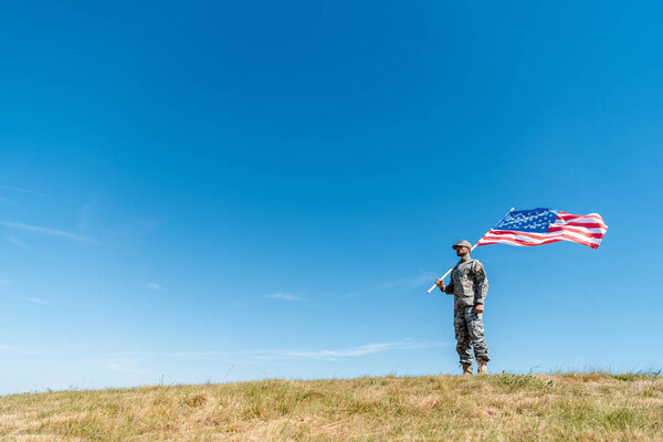 Красивый военный в форме держит американский флаг со звездами и полосками
 